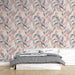Une chambre moderne avec un papier peint floral aux motifs de feuilles colorées dans des teintes douces de rose, gris et beige, créant une atmosphère chaleureuse et accueillante.