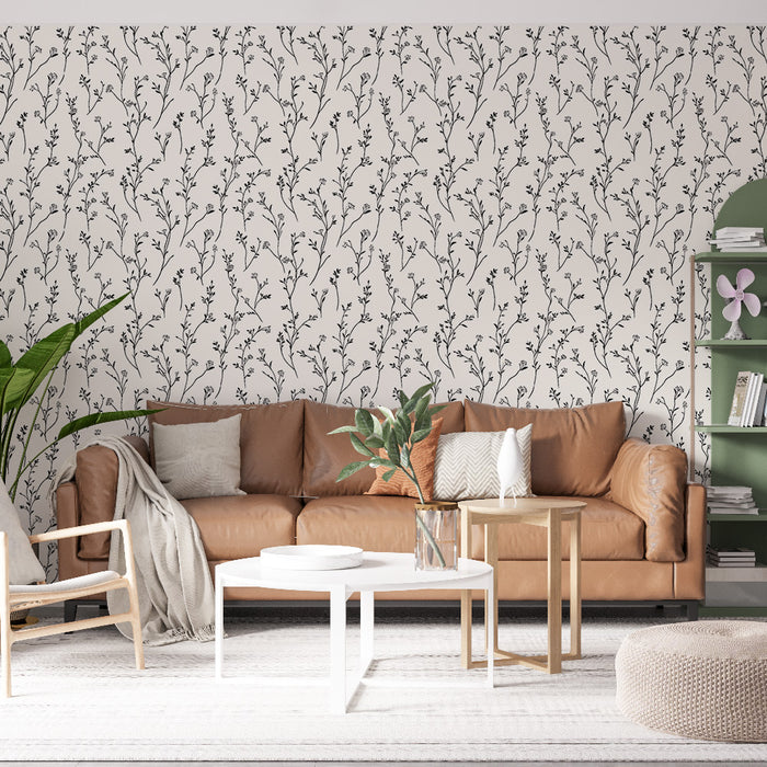 Une pièce de salon avec un papier peint floral noir sur fond crème, créant une ambiance douce et élégante, agrémentée de touches naturelles.