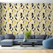 Un salon moderne avec un papier peint aux motifs floraux stylisés en noir et jaune sur fond crème, créant une ambiance chaleureuse et accueillante.