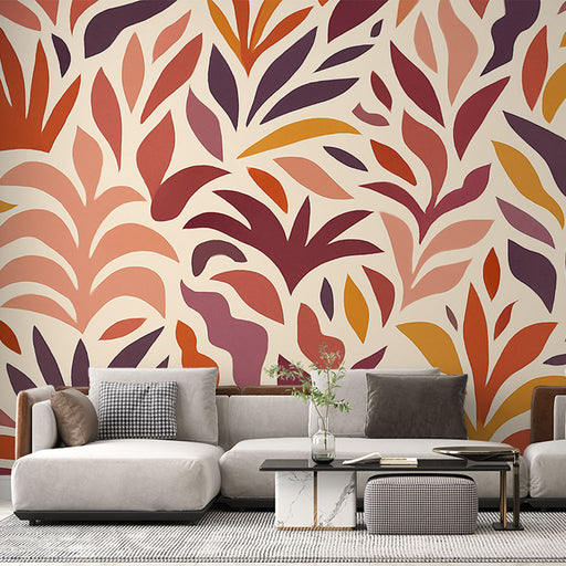 Un salon moderne avec un papier peint aux motifs de feuilles stylisées dans des teintes chaudes de rouge, orange et violet, créant une atmosphère dynamique et accueillante.