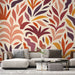 Un salon moderne avec un papier peint aux motifs de feuilles stylisées dans des teintes chaudes de rouge, orange et violet, créant une atmosphère dynamique et accueillante.