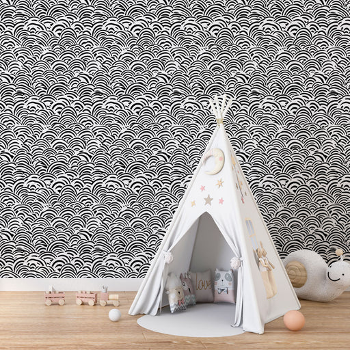 Une chambre d'enfant avec un papier peint noir et blanc aux motifs ondulés évoquant une ambiance ludique et moderne.
