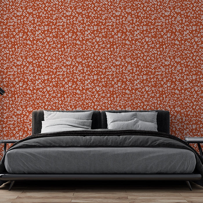 Une chambre moderne avec un papier peint terracotta orné de petites fleurs blanches, créant une atmosphère chaleureuse et accueillante.