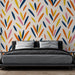 Une chambre moderne avec un papier peint aux motifs abstraits colorés, mêlant des teintes vives de bleu, orange, rose et jaune sur fond clair, créant une ambiance dynamique et joyeuse.