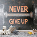 Une chambre moderne avec un papier peint inspirant représentant un haltère et le message "NEVER GIVE UP" dans des teintes cuivrées sur fond noir.