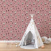 Une chambre d'enfant avec un papier peint rose illustré de moutons et de fleurs délicates, créant une atmosphère douce et ludique.