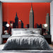 Une chambre moderne avec un papier peint représentant une skyline urbaine sur fond rouge, créant une ambiance dynamique et contemporaine.