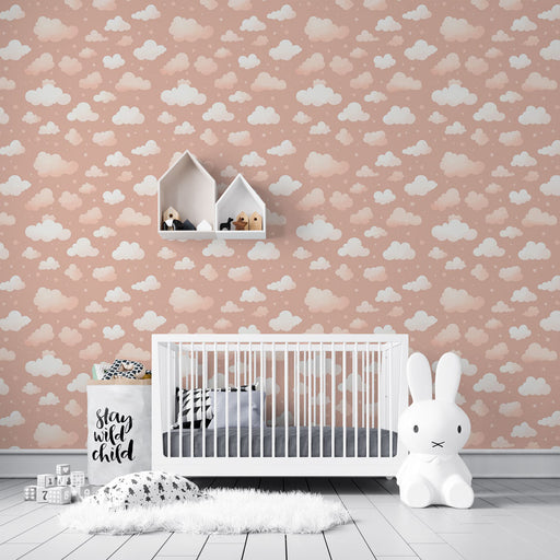 Une chambre d'enfant avec un papier peint rose pâle orné de nuages blancs, créant une atmosphère douce et rêveuse.