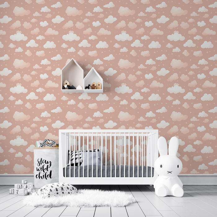 Une chambre d'enfant avec un papier peint rose pâle orné de nuages blancs, créant une atmosphère douce et rêveuse.