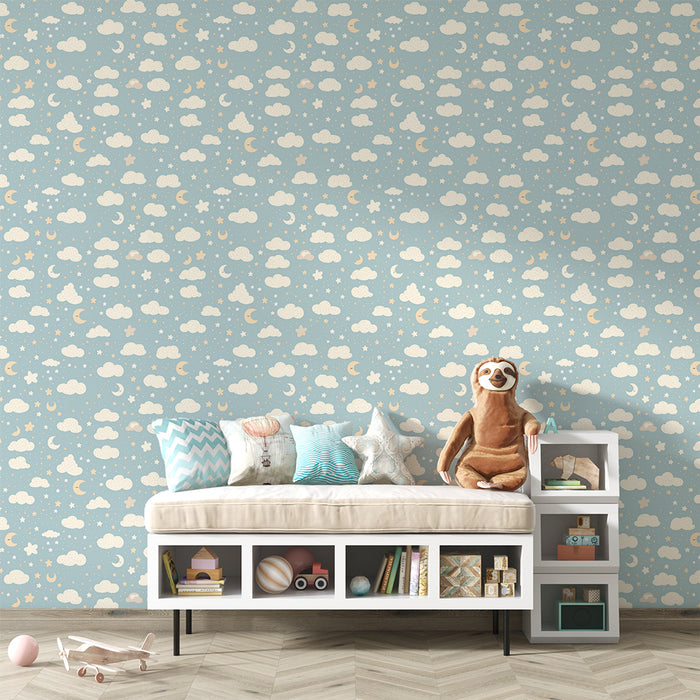 Une chambre enfantine avec un papier peint bleu clair orné de nuages, étoiles et lunes dorées, créant une ambiance douce et rêveuse.