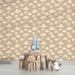 Une chambre d'enfant avec un papier peint illustrant des nuages doux et des étoiles dorées sur fond beige, créant une ambiance rêveuse et chaleureuse.