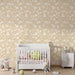 Une chambre d'enfant avec un papier peint beige orné de nuages et d'étoiles blanches, créant une ambiance douce et rêveuse.