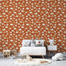 Une chambre d'enfant avec un papier peint terracotta orné de nuages crème et de petites étoiles, créant une atmosphère douce et ludique.