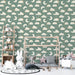 Une chambre d'enfant avec un papier peint illustrant des nuages et des lunes souriants sur fond vert, créant une atmosphère douce et rêveuse.