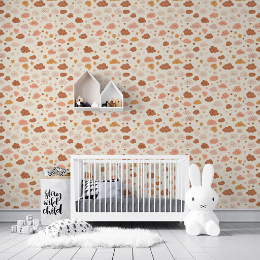 Une chambre d'enfant avec un papier peint ludique représentant des nuages souriants dans des teintes douces de rose, beige et marron, créant une ambiance joyeuse et chaleureuse.