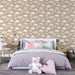 Une chambre douce avec un papier peint beige orné de nuages blancs et d'étoiles, créant une ambiance apaisante et rêveuse.