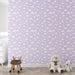 Une chambre d'enfant avec un papier peint lilas orné de nuages blancs, créant une ambiance douce et rêveuse, idéale pour apaiser et stimuler l'imagination.