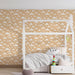 Une chambre d'enfant avec un papier peint beige illustré de nuages blancs, créant une atmosphère douce et rêveuse.