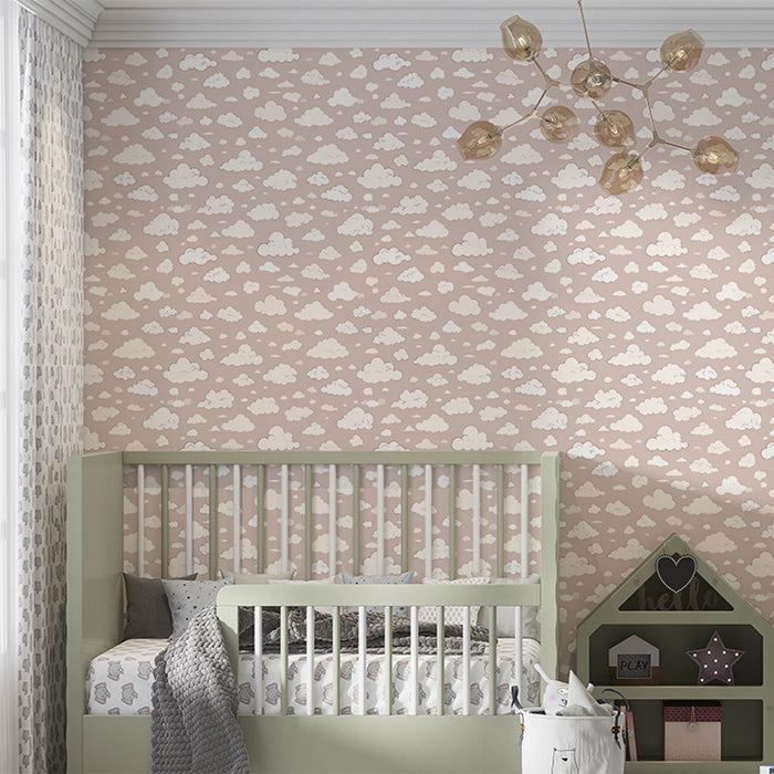 Une chambre d'enfant avec un papier peint rose pâle orné de nuages blancs, créant une atmosphère douce et rêveuse.