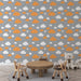 Une chambre d'enfant avec un papier peint aux motifs de nuages blancs et orange sur fond gris, créant une atmosphère joyeuse et ludique.