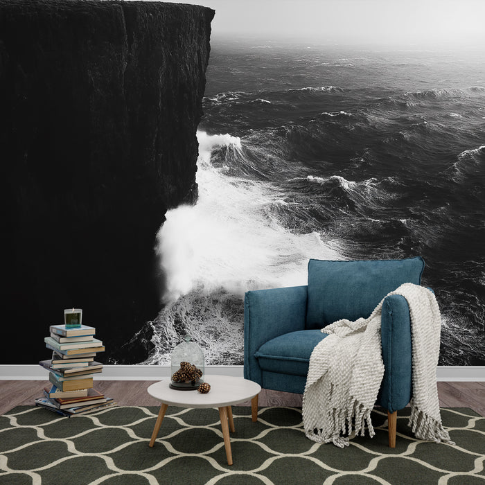 Une pièce de salon avec un papier peint en noir et blanc représentant une falaise surplombant des vagues tumultueuses, créant une ambiance dramatique et apaisante.