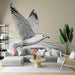 Un salon moderne avec un papier peint représentant un oiseau en vol en noir et blanc, créant une ambiance aérienne et apaisante.