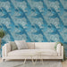 Un salon lumineux avec un papier peint tropical bleu représentant des perroquets en vol sur un fond de feuillage, créant une atmosphère vivante et exotique.