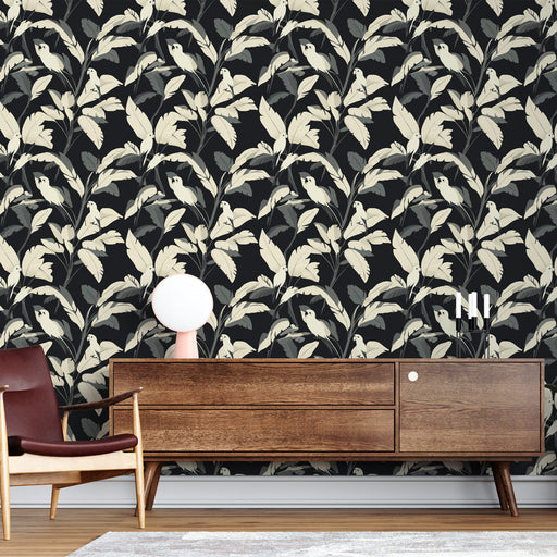 Un salon moderne avec un papier peint floral représentant des feuilles et des oiseaux sur fond noir, créant une ambiance élégante et chaleureuse.