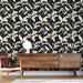 Un salon moderne avec un papier peint floral représentant des feuilles et des oiseaux sur fond noir, créant une ambiance élégante et chaleureuse.