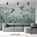Un salon moderne avec un papier peint tropical aux teintes douces de vert et or, représentant des oiseaux et des feuillages, créant une ambiance sereine et naturelle.