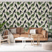 Un salon accueillant avec un papier peint tropical représentant des oiseaux noirs perchés sur de grandes feuilles vertes et des fleurs blanches, créant une ambiance vivante et naturelle.