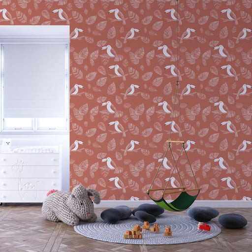 Une chambre d'enfant avec un papier peint terracotta orné de motifs de feuilles et d'oiseaux blancs, créant une ambiance chaleureuse et ludique.