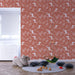 Une chambre d'enfant avec un papier peint terracotta orné de motifs de feuilles et d'oiseaux blancs, créant une ambiance chaleureuse et ludique.