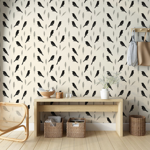 Une pièce lumineuse avec un papier peint illustrant des oiseaux noirs et des plumes sur un fond crème, créant une atmosphère douce et naturelle.