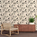Une salle de séjour avec un papier peint délicat représentant des oiseaux noirs sur des branches fleuries, créant une atmosphère élégante et apaisante.
