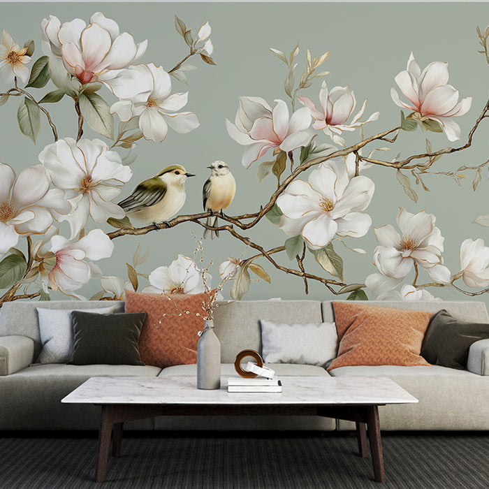Une pièce de vie élégante avec un papier peint floral représentant des magnolias blancs et des oiseaux délicats sur un fond vert apaisant.