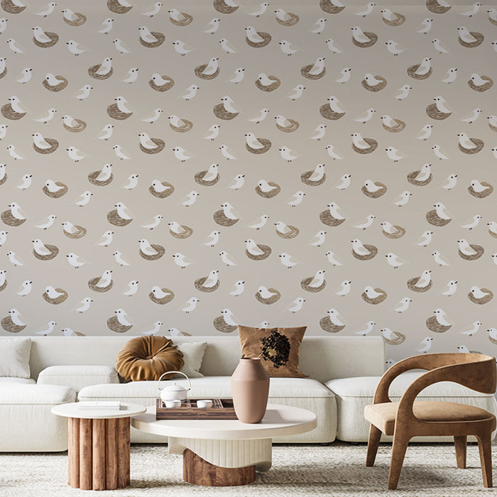 Un salon lumineux avec un papier peint doux représentant des oiseaux blancs et des nids dans des teintes beige et brune, créant une ambiance chaleureuse et accueillante.