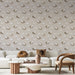 Un salon lumineux avec un papier peint doux représentant des oiseaux blancs et des nids dans des teintes beige et brune, créant une ambiance chaleureuse et accueillante.