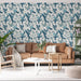 Un salon lumineux avec un papier peint tropical représentant des perroquets et des feuillages dans des teintes de bleu sur fond clair, créant une ambiance vivante et apaisante.