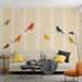 Un salon moderne avec un papier peint illustrant des oiseaux colorés sur un fond beige, créant une ambiance joyeuse et accueillante.