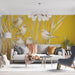 Un salon lumineux avec un papier peint jaune illustrant des oiseaux stylisés perchés dans des herbes, créant une ambiance joyeuse et naturelle.