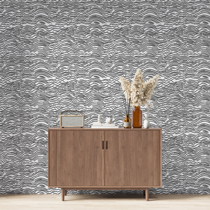 Un salon contemporain avec un papier peint aux motifs ondulés noirs et blancs créant une ambiance dynamique et moderne.