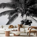 Un salon moderne avec un papier peint noir et blanc représentant des palmiers et des noix de coco, créant une ambiance tropicale et élégante.