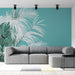 Un salon contemporain avec un papier peint tropical turquoise illustrant de grandes feuilles de palmier blanches, créant une ambiance fraîche et apaisante.