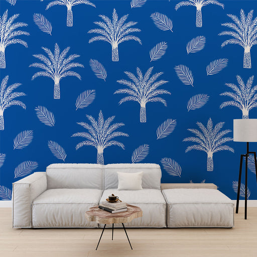 Un salon contemporain avec un papier peint bleu vif orné de motifs de palmiers blancs et de feuilles, créant une ambiance tropicale et vivante.