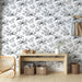 Une pièce lumineuse avec un papier peint noir et blanc illustrant des branches délicates et des paresseux, créant une ambiance ludique et naturelle.
