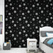 Une chambre moderne avec un papier peint noir orné de têtes de pandas et d'étoiles blanches, créant une ambiance ludique et originale.