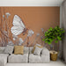 Un salon moderne avec un papier peint illustrant un papillon stylisé sur un fond brun, entouré de fleurs délicates, créant une ambiance douce et naturelle.