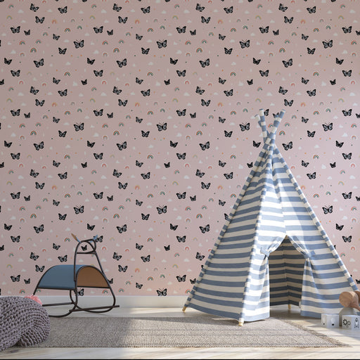 Une chambre d'enfant avec un papier peint rose orné de papillons noirs et de petits arcs-en-ciel, créant une ambiance joyeuse et ludique.