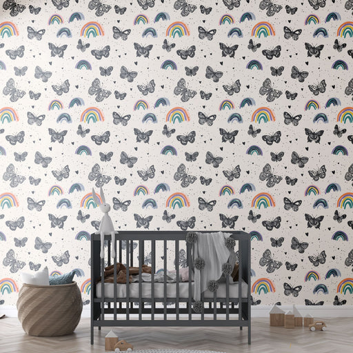Une chambre d'enfant avec un papier peint ludique représentant des papillons noirs et des arcs-en-ciel colorés sur un fond clair, créant une atmosphère joyeuse et imaginative.